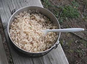 ramen noodles cooked in a pot over campfire