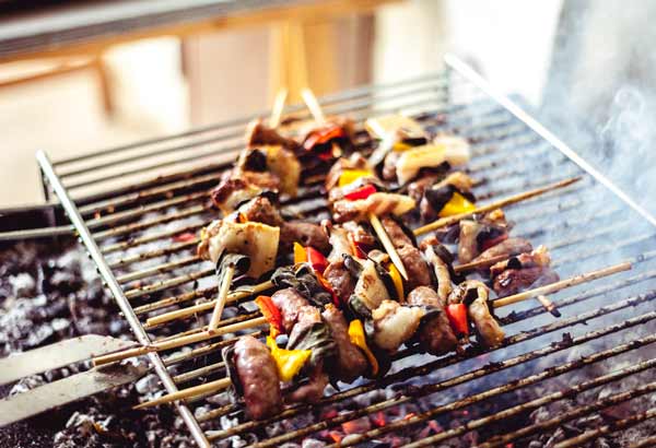 meat and vegetable skewers over a campfire grill