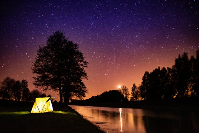 tent camping near a lake at sunset