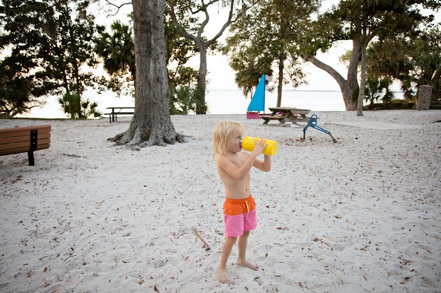 child drinking water on the beach