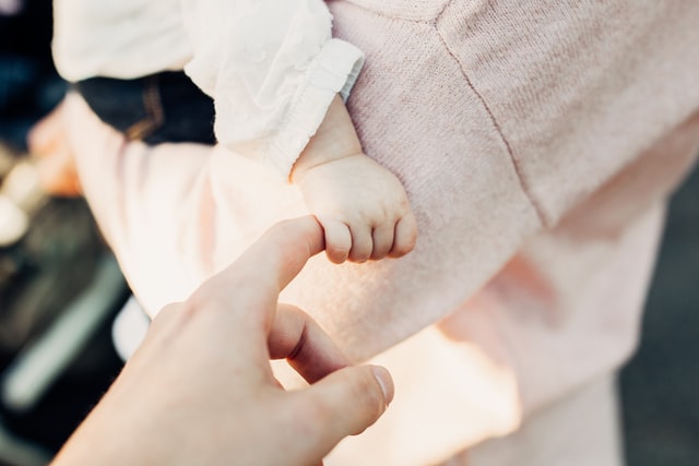 baby holding finger of an adult