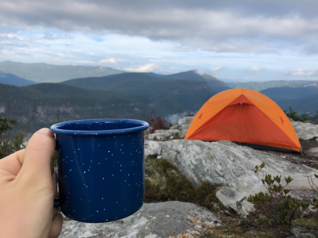 enjoying a fresh cup of hot coffee made with a percolator on a camping trip
