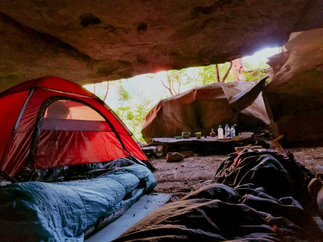 insulated tents and campsite set up beneath a stone overhang