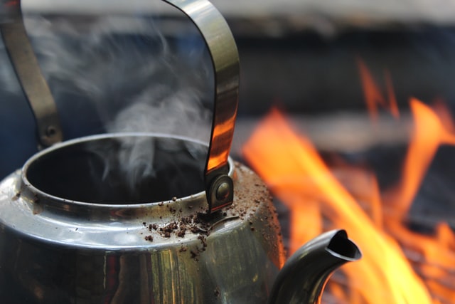 kettle boiling water over a campfire on an outdoors camping trip